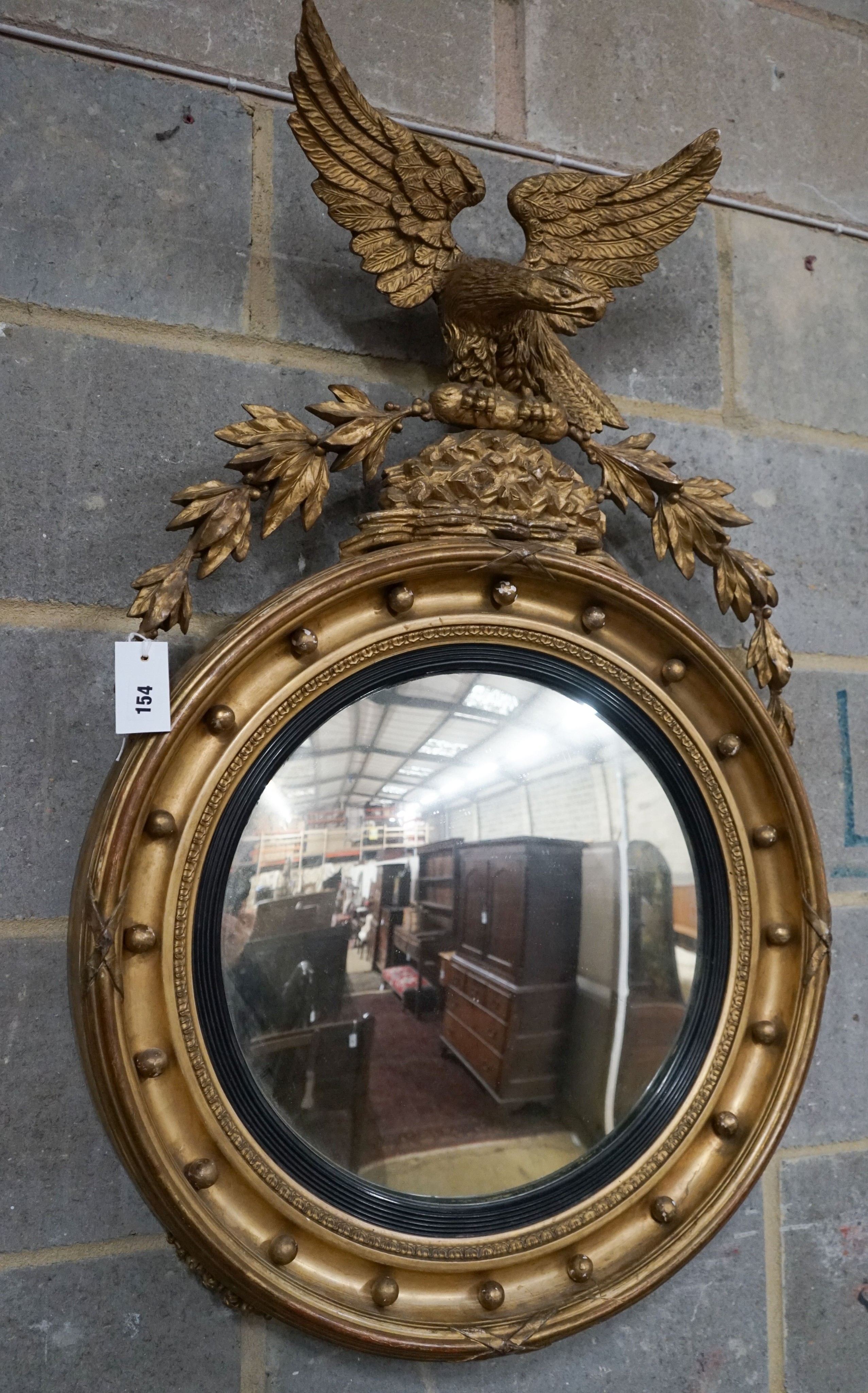 A Regency giltwood and gesso convex wall mirror with eagle pediment, width 60cm, height 94cm
